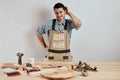 Emotional male carpenter in workwear and apron having confused puzzled look