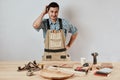 Emotional male carpenter in workwear and apron having confused puzzled look