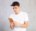 Emotional male student writing message on smartphone screen