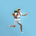 Emotional male tourist with backpack and camera jumping on turquoise background