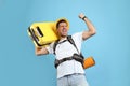 Emotional male tourist with travel backpack and suitcase on turquoise background