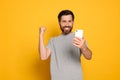 Emotional man looking at smartphone on yellow background Royalty Free Stock Photo