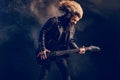 Emotional man rock guitar player with long hair and beard plays on the smoke background. Studio shot