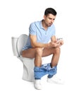 Emotional man with smartphone sitting on toilet bowl Royalty Free Stock Photo