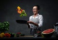 Emotional mature female chef tossing chopped vegetables from a pan