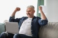 Emotional mature man with laptop raising hands up Royalty Free Stock Photo