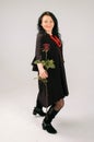 Emotional Middle-aged Woman with Red Rose Dancing in Studio in Black Dress and Ethnic Necklace Royalty Free Stock Photo