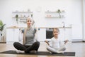 Happy young mom and baby girl exercising together with joy on mat at home. Royalty Free Stock Photo