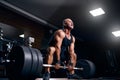 Emotional older bodybuilder preparing to exercise deadlift with barbell on cross training in gym