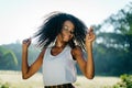 Emotional outdoor portrait. The charming young african girl with pretty smile and green eye shadows is shaking her curly Royalty Free Stock Photo