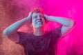 Emotional pain. Young man in deep emotional shock  over pink background with clouds of smoke. Concept of mental Royalty Free Stock Photo