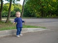 Emotional portrait of an annoyed little blonde girl on a summer day in a city park. Beautiful capricious child