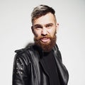 Emotional portrait of a bearded young man in a leather jacket in the studio