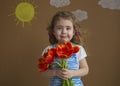 Emotional portrait beautiful girl in the blue dress with flowers tulips in hands on a light background with painted sun Royalty Free Stock Photo