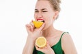 Emotional portrait of a beautiful girl on an isolated white background who is eating a lemon. The concept of a healthy Royalty Free Stock Photo