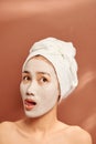 Emotional portrait of a happy and positive beautiful nude young woman with a clay cosmetic mask on her face Royalty Free Stock Photo