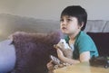 Emotional portrait of kid sitting on sofa hugging his soft toy looking up with worrying face,Child with sad face while watching Royalty Free Stock Photo