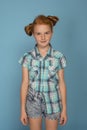 Emotional portrait of a little funny naughty girl with red hair against blue background