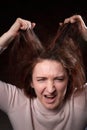 Emotional portrait of middle age woman on black background. Female model geting angry toughting her hair while posing in the Royalty Free Stock Photo