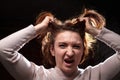 Emotional portrait of middle age woman on black background. Female model geting angry toughting her hair while posing in the Royalty Free Stock Photo