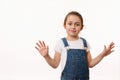 Emotional portrait of a cute baby girl, wearing blue denim overalls, sweetly smiling, showing her hands palms to camera Royalty Free Stock Photo