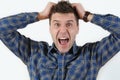 Emotional portrait of young angry screaming man pulling his hair