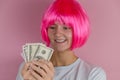 young beautiful happy woman with pink hair holding dollars on a pink background Royalty Free Stock Photo