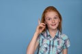 Emotional portrait of a young funny naughty girl with red hair against blue background