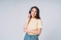 Emotional portrait of Young happy asian woman with long hair in yellow shirt and jeans listening music by headphones on grey Royalty Free Stock Photo