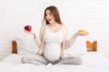 Pregnant woman choosing between croissant and apple Royalty Free Stock Photo