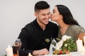 Emotional pretty lady holding flowers and kissing her handsome boyfriend