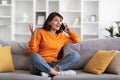 Emotional pretty young indian woman talking on phone at home Royalty Free Stock Photo