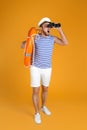 Emotional sailor with binoculars and ring buoy on yellow background