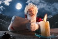 Emotional Santa Claus congratulating with New Year and Christmas, sending a letter, wish list in midnight with candle Royalty Free Stock Photo