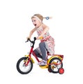 Emotional screaming little girl in a floral dress rides a children`s bike, isolated on white background.