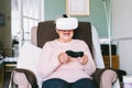 Emotional senior woman wearing virtual reality goggles and using wireless controller, joystick gamepad playing video games at home Royalty Free Stock Photo