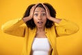 Emotional shocked black lady touching her face and looking at camera with open mouth over yellow studio background Royalty Free Stock Photo