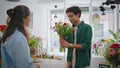 Emotional shopper give flower present gift to beautiful florist woman in store. Royalty Free Stock Photo