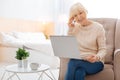 Emotional smart pensioner talking on the phone while sitting with a laptop