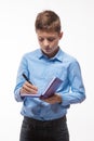 Emotional teenager boy brunette in a blue shirt with a diary and a pen in hand