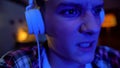 Emotional teenager playing video game night, awkward age, face mimics close-up