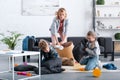 emotional tired mother putting toys in basket while naughty kids fighting