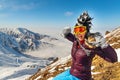 Emotional traveler young woman with windy hair smiling, sitting on top of sunny mountains. Funny woman in mohawk hat.