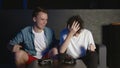 Emotional two young guys are sitting on the couch in front of the TV and excited playing a game console. Left one man Royalty Free Stock Photo