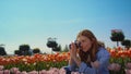 Emotional woman looking at blooming garden. Happy girl taking photo of flowers.