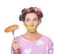 Emotional woman with measuring tape around her mouth and tasty croissant on white background. Diet concept