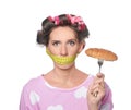 Emotional woman with measuring tape around her mouth and tasty croissant on white background. Diet concept