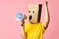 Emotional woman with paper bag on head making announcement with megaphone in hands