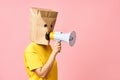 Emotional woman with paper bag on head making announcement with megaphone in hands