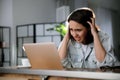 Emotional woman working on laptop in office. Online hate concept